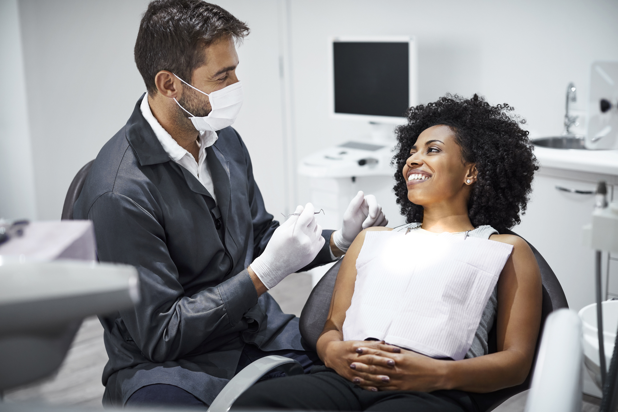 Dentist examining smiling female patient in clinic